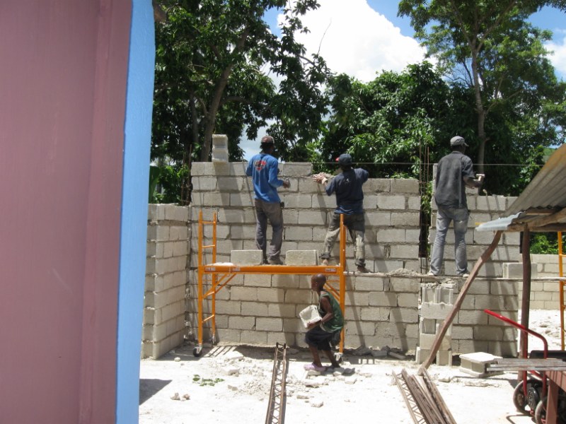 Men and boy hard at work on the mission house walls.